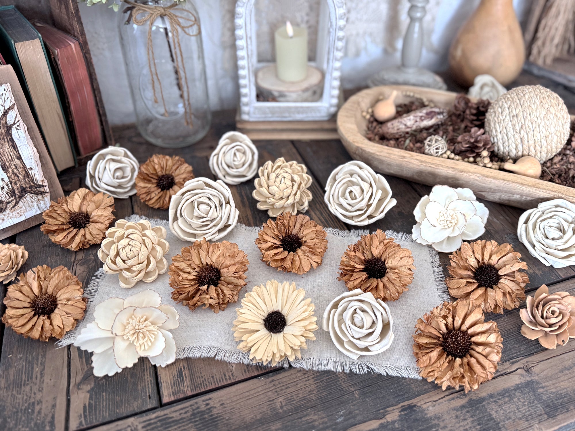 Decorative wood flower blossoms in beige and spicey yellow on a wooden surface with a candle and books in the background.