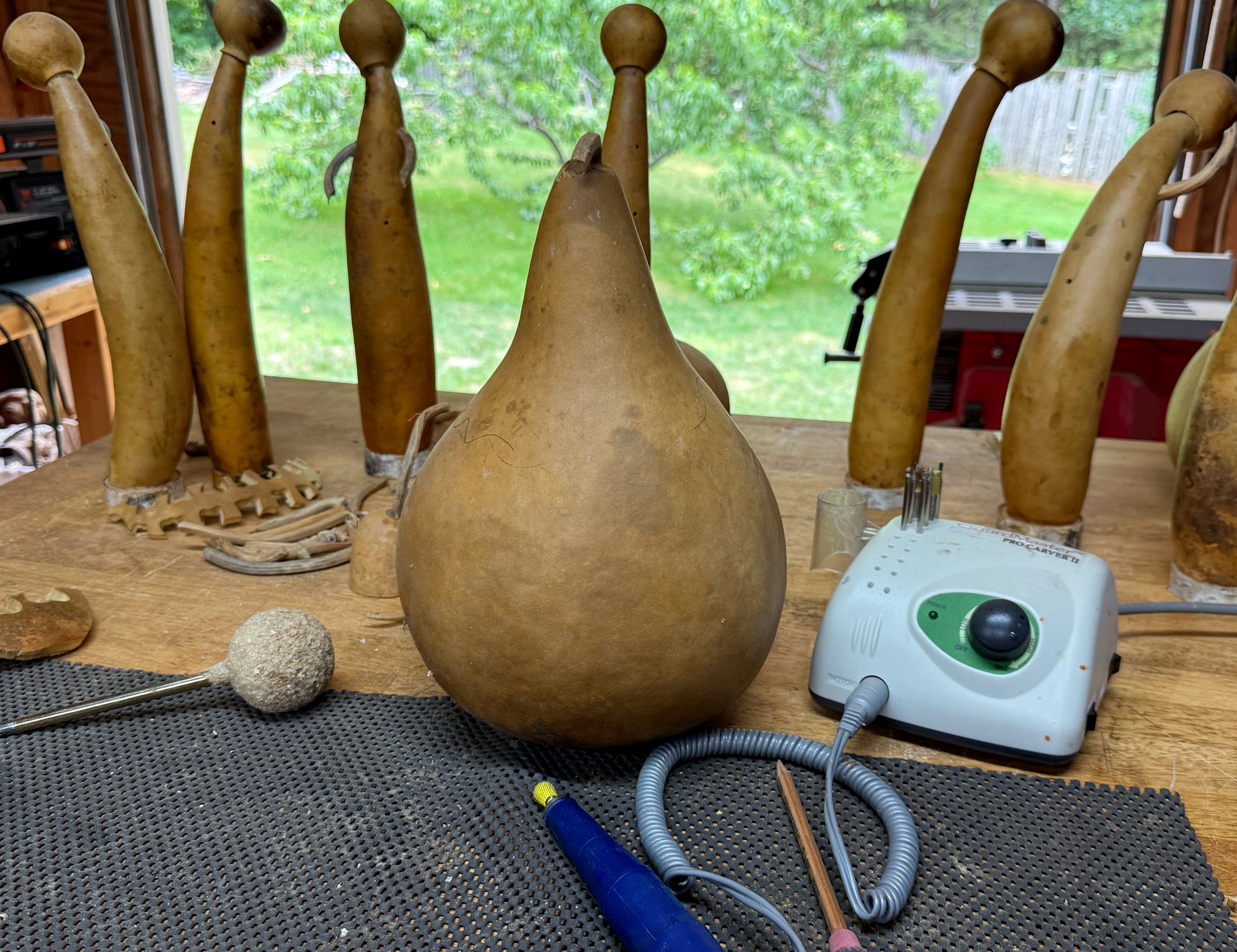 Gourds and a small electronic device on a table with a window in the background
