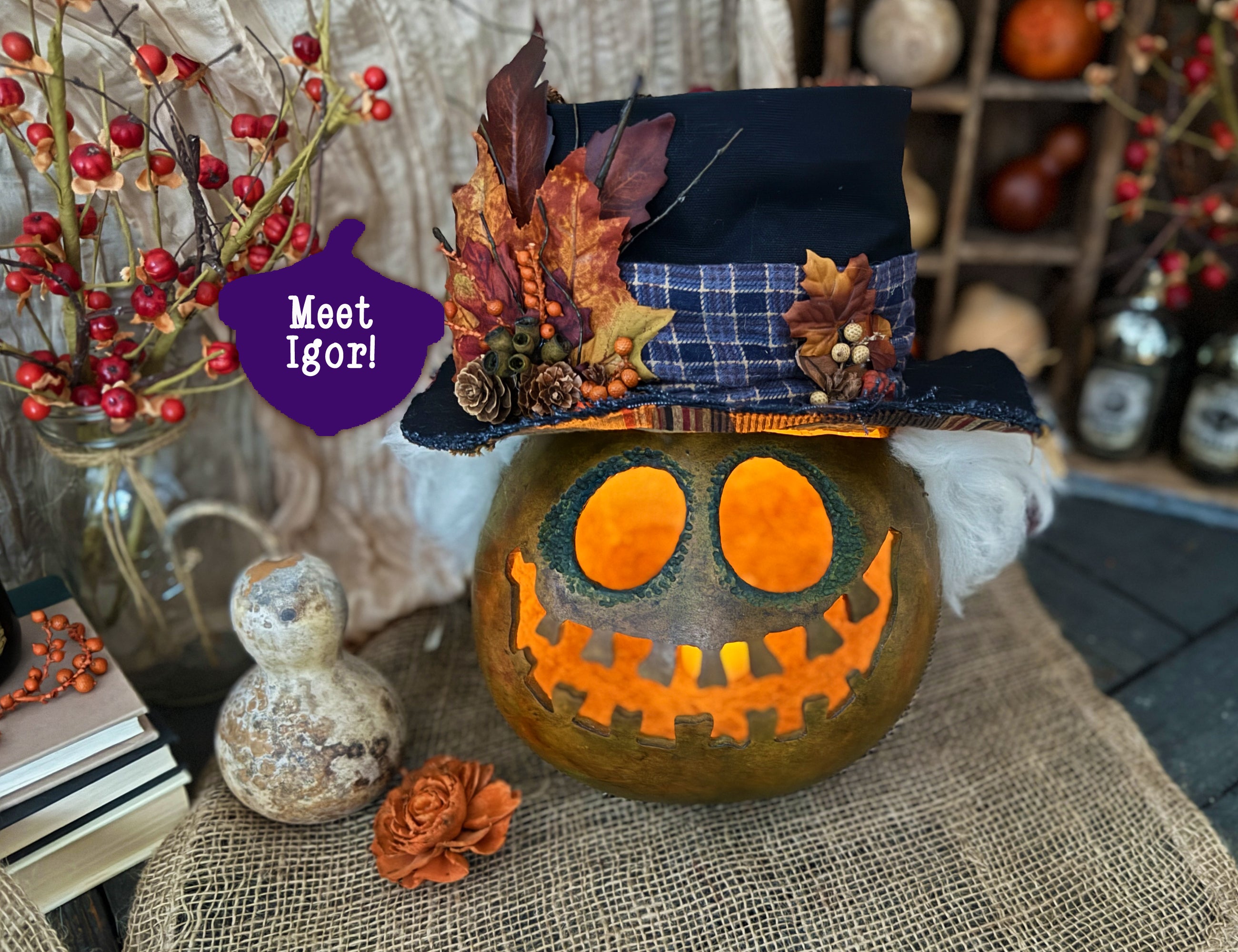 Decorative pumpkin gourd with a top hat and autumn leaves on a table with pumpkins and berries in the background.