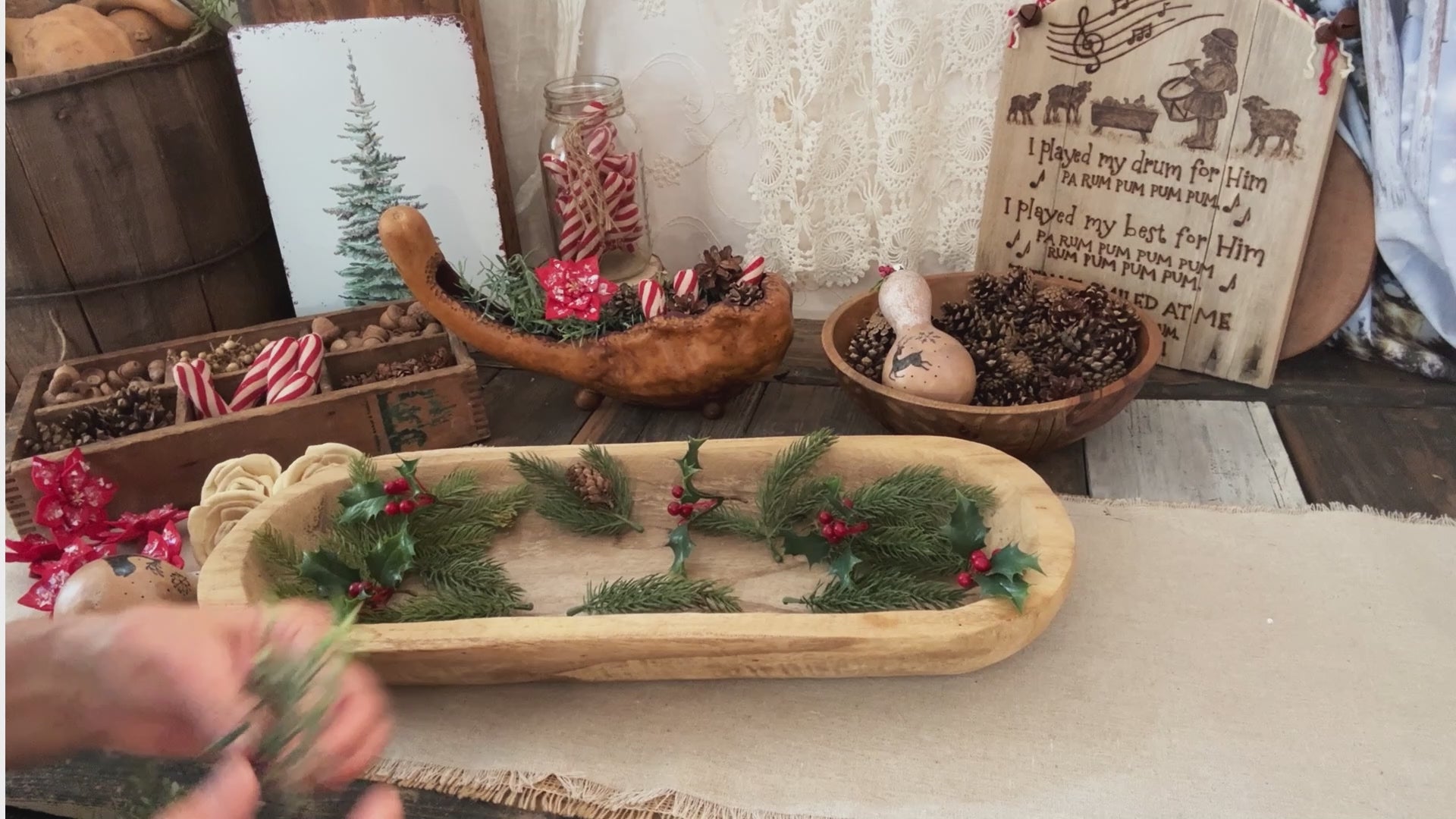 A Christmas dough bowl arrangement being created with rosemary, holly berry and spruce greenery. 