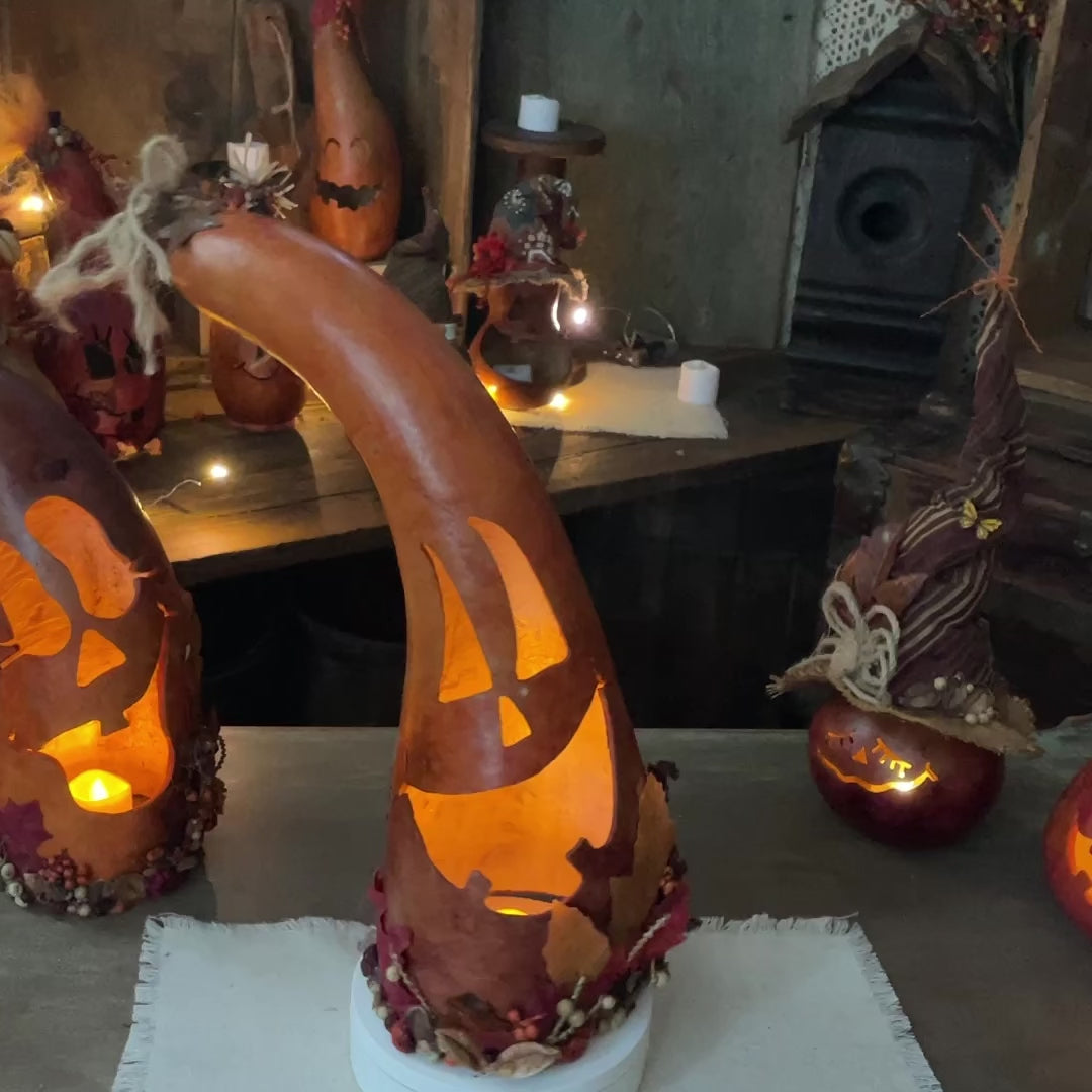 Tall bent gourd made into a pumpkin Halloween decoration with candle